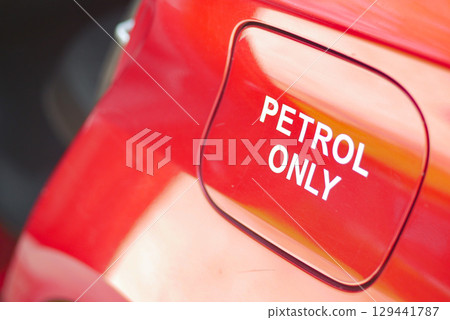 Petrol only warning label on a bright red fuel cap 129441787