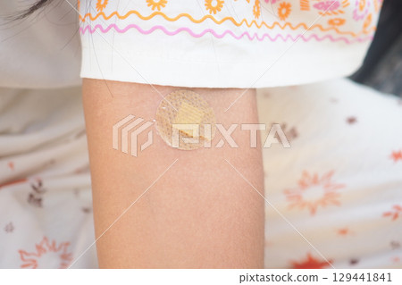 Child receives a bandage on scraped arm during outdoor play 129441841