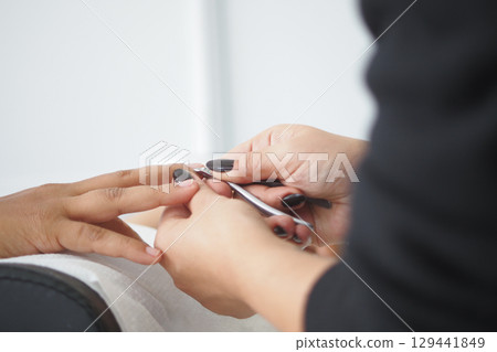 Nail technician performing manicure on client in salon 129441849