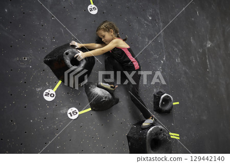 Determined girl climbing artificial wall at Determined girl climbing artificial wall at 129442140