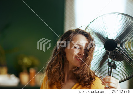 Woman Finding Comfort from Fan\'s Breeze Woman Finding Comfort from Fan\'s Breeze 129442556