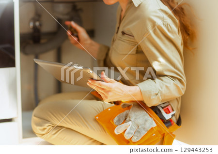 Woman Plumber Inspecting Under Sink Woman Plumber Inspecting Under Sink 129443253