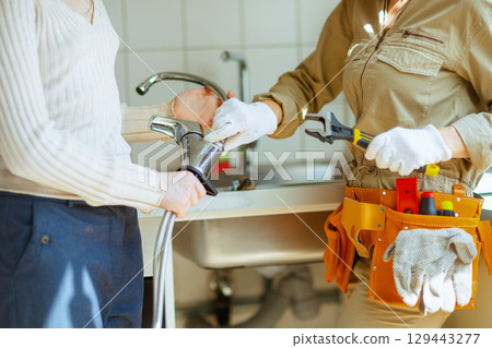 Plumber and homeowner remove old faucet after fix 129443277