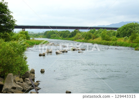 The gentle flow of the Kinokawa River in Wakayama Prefecture and a bridge visible in the distance 129443315