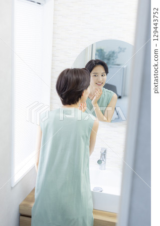 A woman in the bathroom doing skin care 129443752