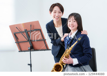 Portrait of a female student and teacher holding a saxophone 129444080