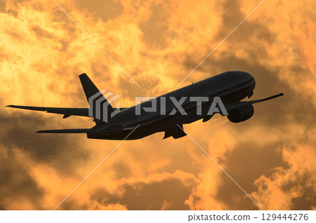Planes taking off and landing against the backdrop of a sunset 129444276