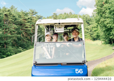 Golfer man and woman riding a golf cart on a golf course 129444410