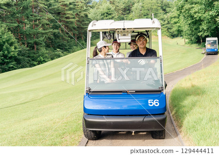 Golfer man and woman riding a golf cart on a golf course 129444411