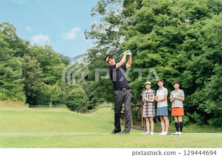 一名男高爾夫球手在高爾夫球場上開球，他的同伴在一旁觀看他的揮桿動作 129444694