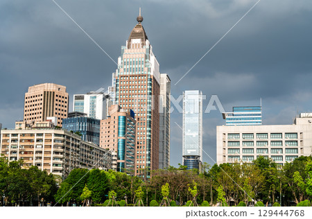View of modern skyscrapers and office buildings in the Taipei city skyline, seen over a lush green park on a cloudy day in Taiwan View of modern skyscrapers and office buildings in the Taipei city skyline, seen over a lush green park on a cloudy day in Taiwan 129444768