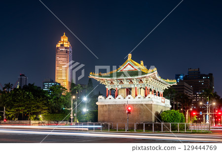 The historic Jingfu Gate (East Gate) in a traffic circle at night, with Taipei modern city skyline and traffic light trails in the background, Taiwan 129444769