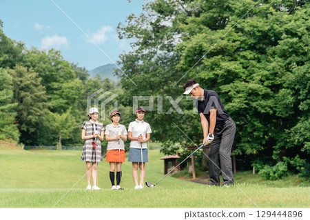 A male golfer hitting a tee shot at a golf course with his companion watching his swing A male golfer hitting a tee shot at a golf course with his companion watching his swing 129444896