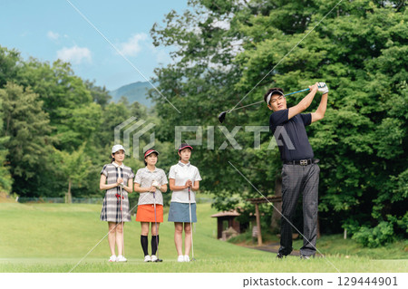 A male golfer hitting a tee shot at a golf course with his companion watching his swing A male golfer hitting a tee shot at a golf course with his companion watching his swing 129444901