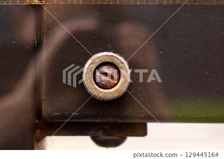 This is a detailed close up view of a screw situated on a piece of metal 129445164