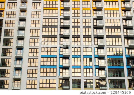 There exists a very tall building that features numerous windows and balconies There exists a very tall building that features numerous windows and balconies 129445169