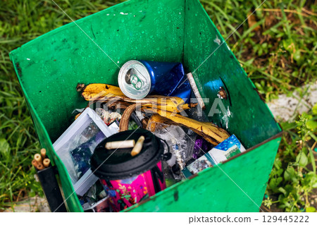 A vibrant green trash can that is overflowing with a lot of trash A vibrant green trash can that is overflowing with a lot of trash 129445222