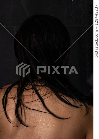 The image captures a womans back, adorned with wet, flowing hair The image captures a womans back, adorned with wet, flowing hair 129445237