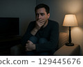 Young man watching TV in a dark room 129445676