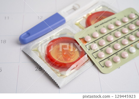 Pregnancy test and condom for female on calendar, ovulation day. 129445923