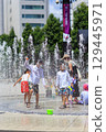 Children enjoying splashing around in the fountain in midsummer 129445971