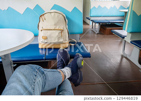 Woman with feet up on train seat next to backpack. Woman with feet up on train seat next to backpack. 129446819