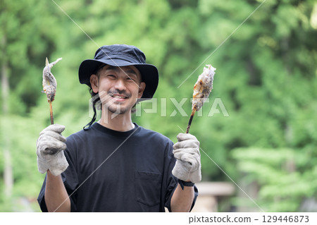 Outdoor man eating river fish at camp 129446873
