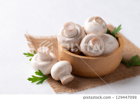White Button mushroom or Champignon mushroom (Agaricus bisporus) in wooden bowl on white background 129447098