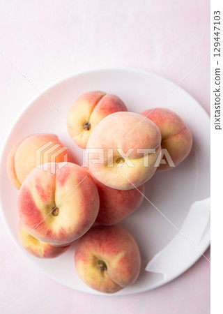 Fresh peaches on white plate with pink background, Summer fruit, Top view Fresh peaches on white plate with pink background, Summer fruit, Top view 129447103