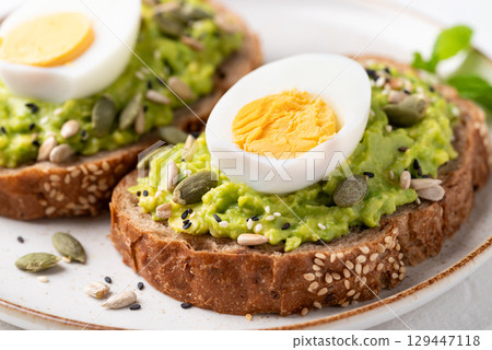 Avocado toast with boiled egg, sunflower seeds, pumpkin seeds and sesame seeds  129447118