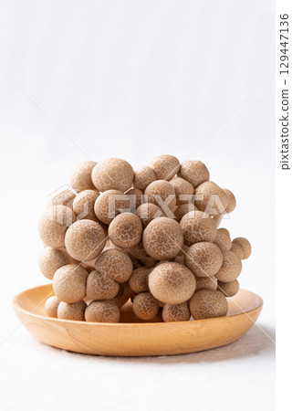 Fresh brown Shimeji mushroom on wooden plate with white background 129447136