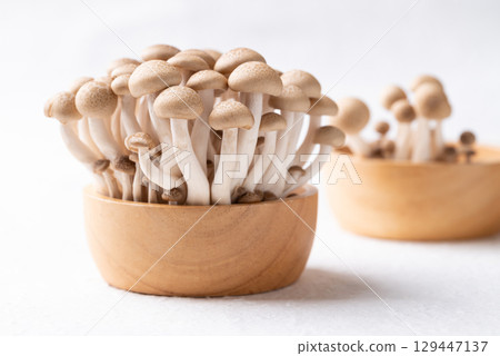 Fresh brown Shimeji mushroom in wooden bowl on white background 129447137