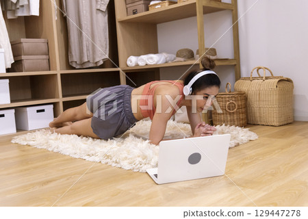 Young Sport Women look at laptop online trainer home fitness workout exercise in living room. Woman using laptop on floor in sportswear arms stretching body weight traning. Healthy lifestyle concept Young Sport Women look at laptop online trainer home fitness workout exercise in living room. Woman using laptop on floor in sportswear arms stretching body weight traning. Healthy lifestyle concept 129447278