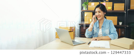 Banner Online seller Close up hands Young asian woman typing laptop keyboard checking online order on stock delivery package. Asian woman startup small business at home office with copy space 129447333