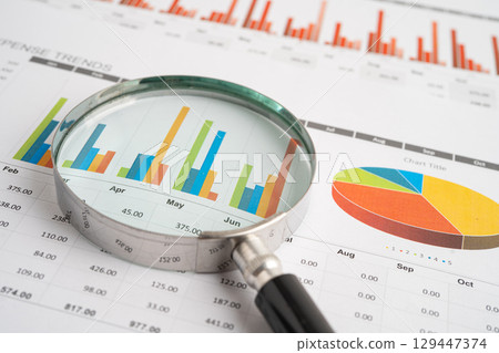 Magnifying glass on spreadsheet and graph paper. Financial data economy, Business. 129447374