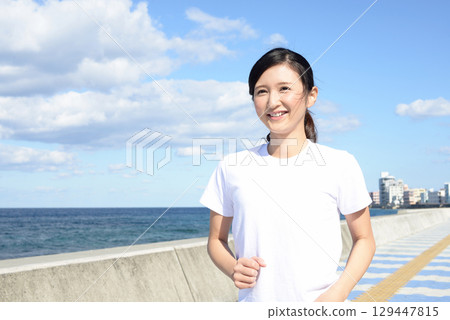 Woman jogging along the seafront Woman jogging along the seafront 129447815