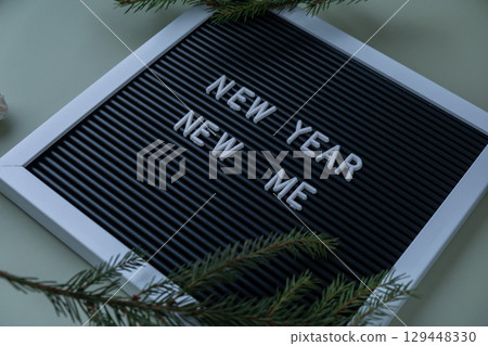 NEW YEAR NEW ME text on black letter board on green background with Christmas decor. New year aims resolutions. Planning and setting goals NEW YEAR NEW ME text on black letter board on green background with Christmas decor. New year aims resolutions. Planning and setting goals 129448330