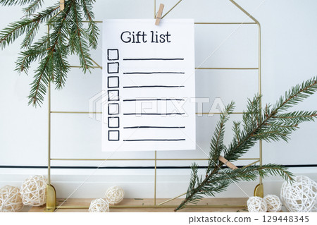 Holiday preparation paper note with GIFT LIST checklist text. Vision board with cozy minimalistic handmade new year Christmas decor Low key festive celebration 129448345