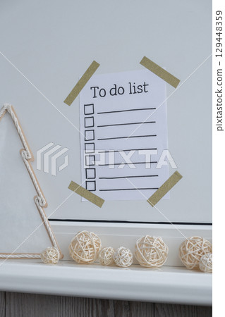 TO DO LIST checklist text on paper note stick on while wall with cozy minimalistic handmade Christmas decor. New year aims resolutions. Low key festive Planning and setting goals TO DO LIST checklist text on paper note stick on while wall with cozy minimalistic handmade Christmas decor. New year aims resolutions. Low key festive Planning and setting goals 129448359
