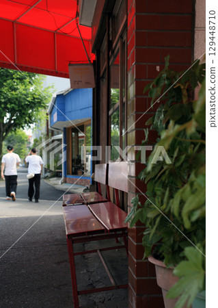 A bench in front of the store and a female passerby A bench in front of the store and a female passerby 129448710