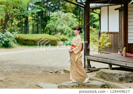 A woman in a kimono strolling through a garden A woman in a kimono strolling through a garden 129449627