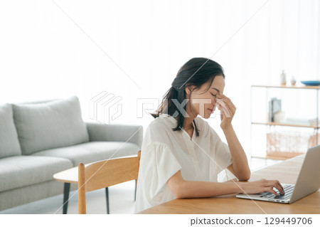 A young woman holding her head in front of a personal computer A young woman holding her head in front of a personal computer 129449706