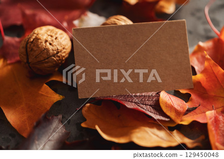 Autumn theme background with leaves over concrete with brown paper card Autumn theme background with leaves over concrete with brown paper card 129450048