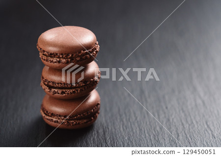 Chocolate macarons stacked on slate board with copy space 129450051