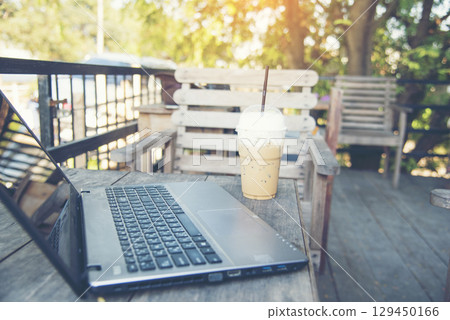 Office laptop business financial document chart and graph on wooden table with coffee cup. Flat lay notebook computer laptop on office desk. No people business graph chart mockup on business workspace 129450166