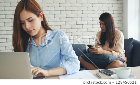 Two asian Female freelance reading financial graph charts Planning analyzing marketing data. Asian people team working office firm. Two businesswomen team meeting using laptop at company office desk. 129450521