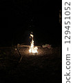 Night campfire in forest. Burning bonfire flames with flying sparks in darkness. Outdoor camping atmosphere with natural firelight glow. Perfect for hiking, camping, wilderness themes. 129451052