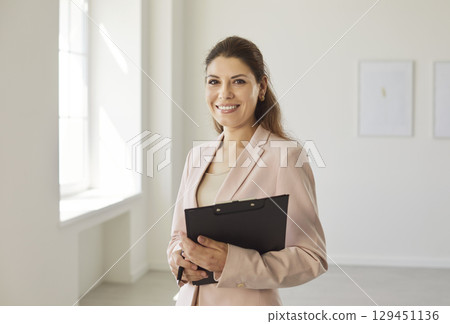 Happy smiling realtor agent standing in new apartments and looking at camera. 129451136