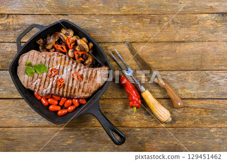 Succulent steak grilled to perfection with mushrooms cherry tomatoes arranged in cast iron skillet. 129451462
