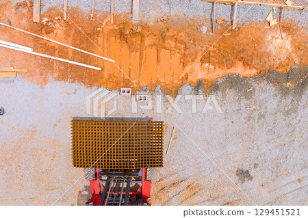 Heavy machinery is positioned on gravel construction site, surrounded by metal mesh construction elements. Heavy machinery is positioned on gravel construction site, surrounded by metal mesh construction elements. 129451521